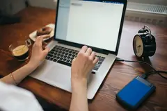 Жена работи на лаптоп с включен външен диск
